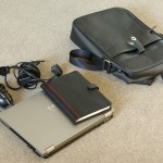 A laptop, charger, mouse and notepad with the bag